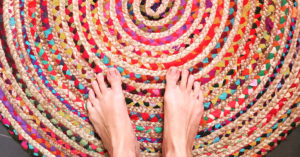 Nackte Füße stehen auf einem kunterbunten Teppich